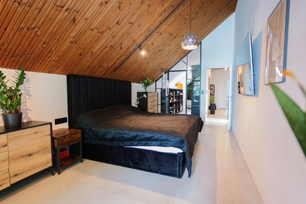 Sypialnia z drewnianym sufitem i meblami z naturalnych materiałów, realizacja Domy na Miarę