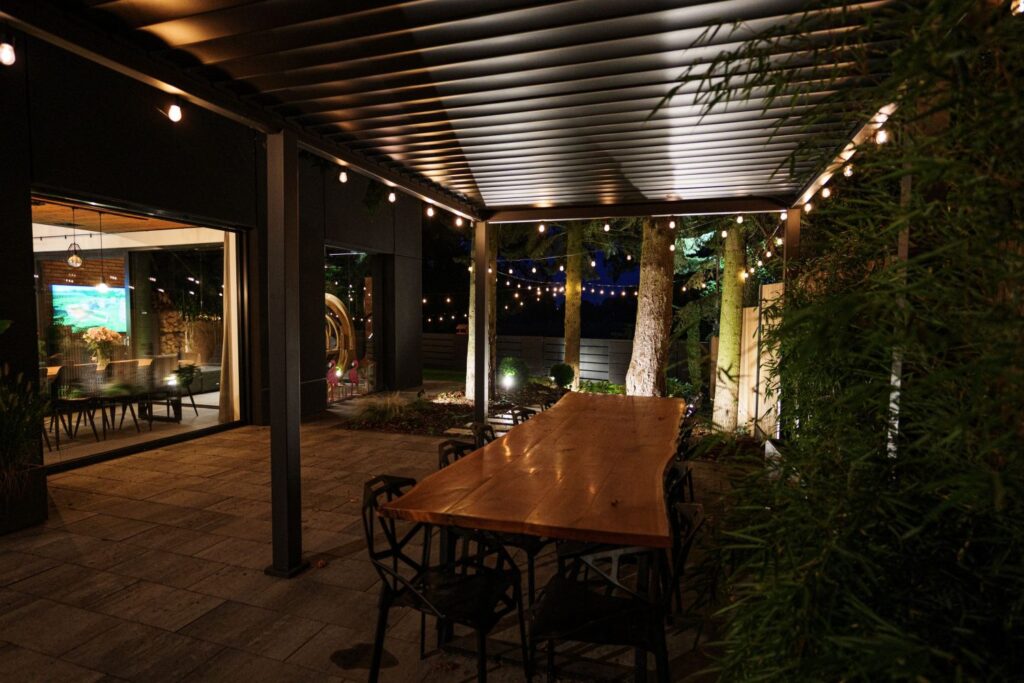 Zadaszony taras dom premium – drewniany stół i oświetlenie ogrodowe