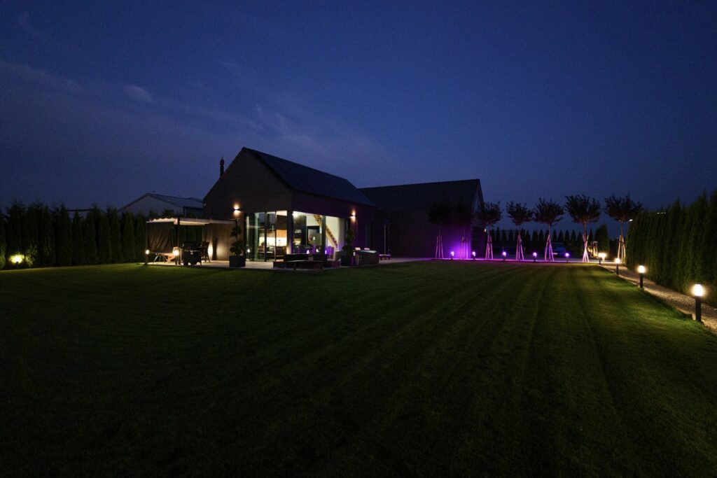 Nowoczesny dom z przeszkloną strefą dzienną i oświetleniem ogrodowym wieczorem