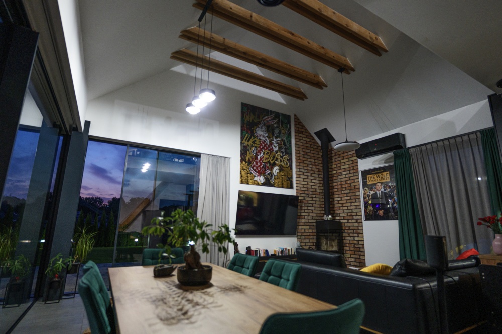 Salon w domu premium z kominkiem, drewnianymi belkami i dużymi przeszkleniami