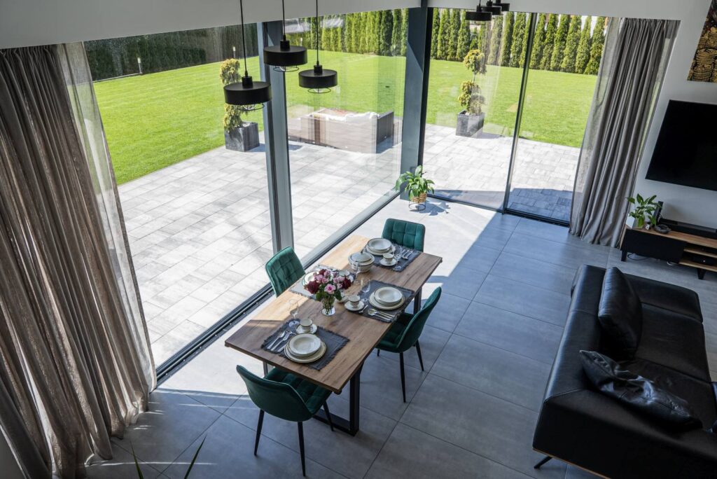 Nowoczesne wnętrze domu jednorodzinnego z dużymi przeszkleniami i jadalnią otwartą na ogród