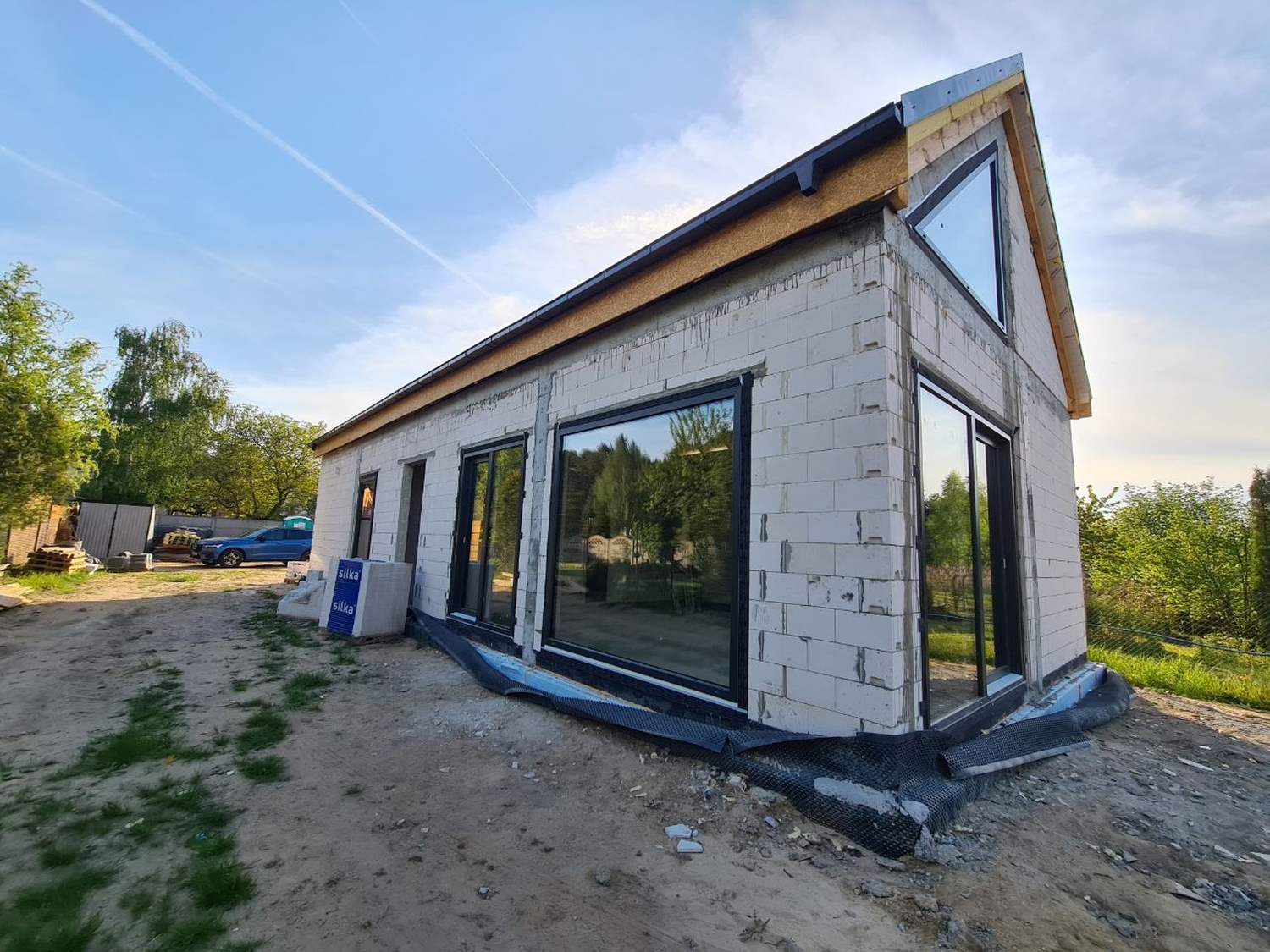 Stan surowy zamknięty – dom jednorodzinny z dachem i oknami w trakcie budowy